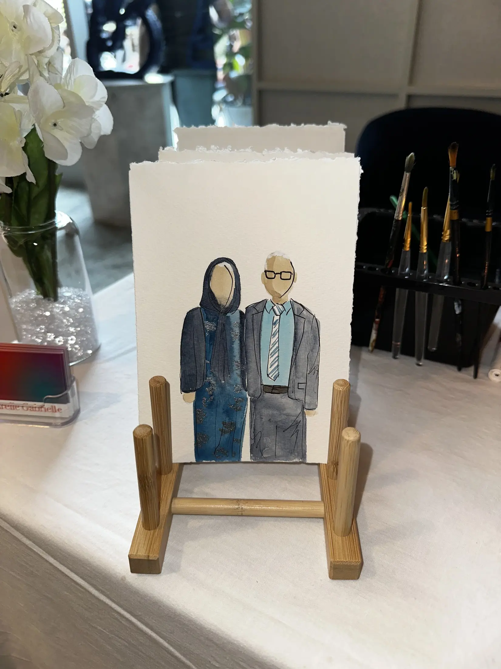 Deux invités en bleu, présentés sur un petit chevalet — aquarelle par Gabrielle