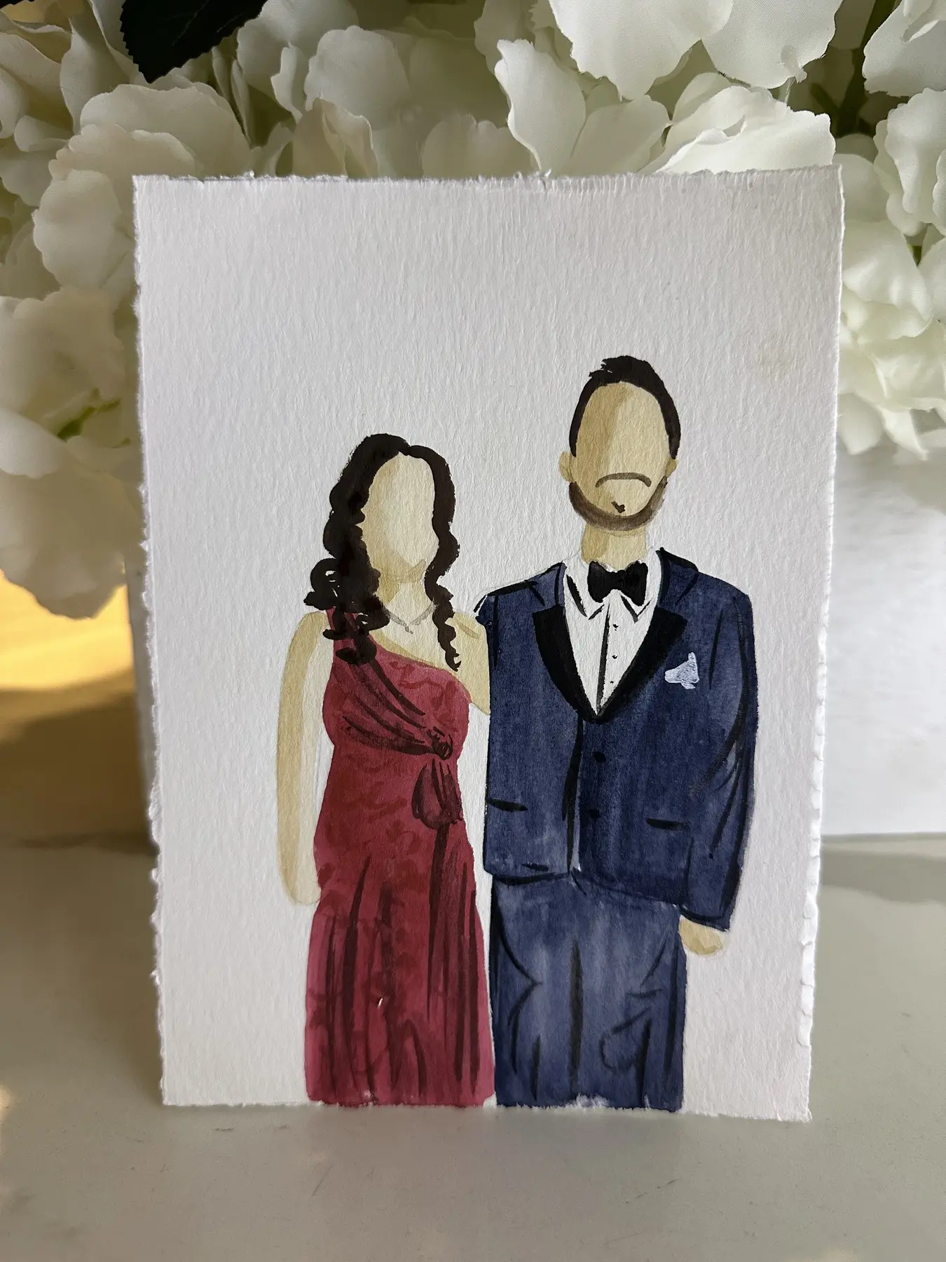 Couple en robe bordeaux et smoking bleu marine parmi des fleurs blanches — aquarelle par Gabrielle