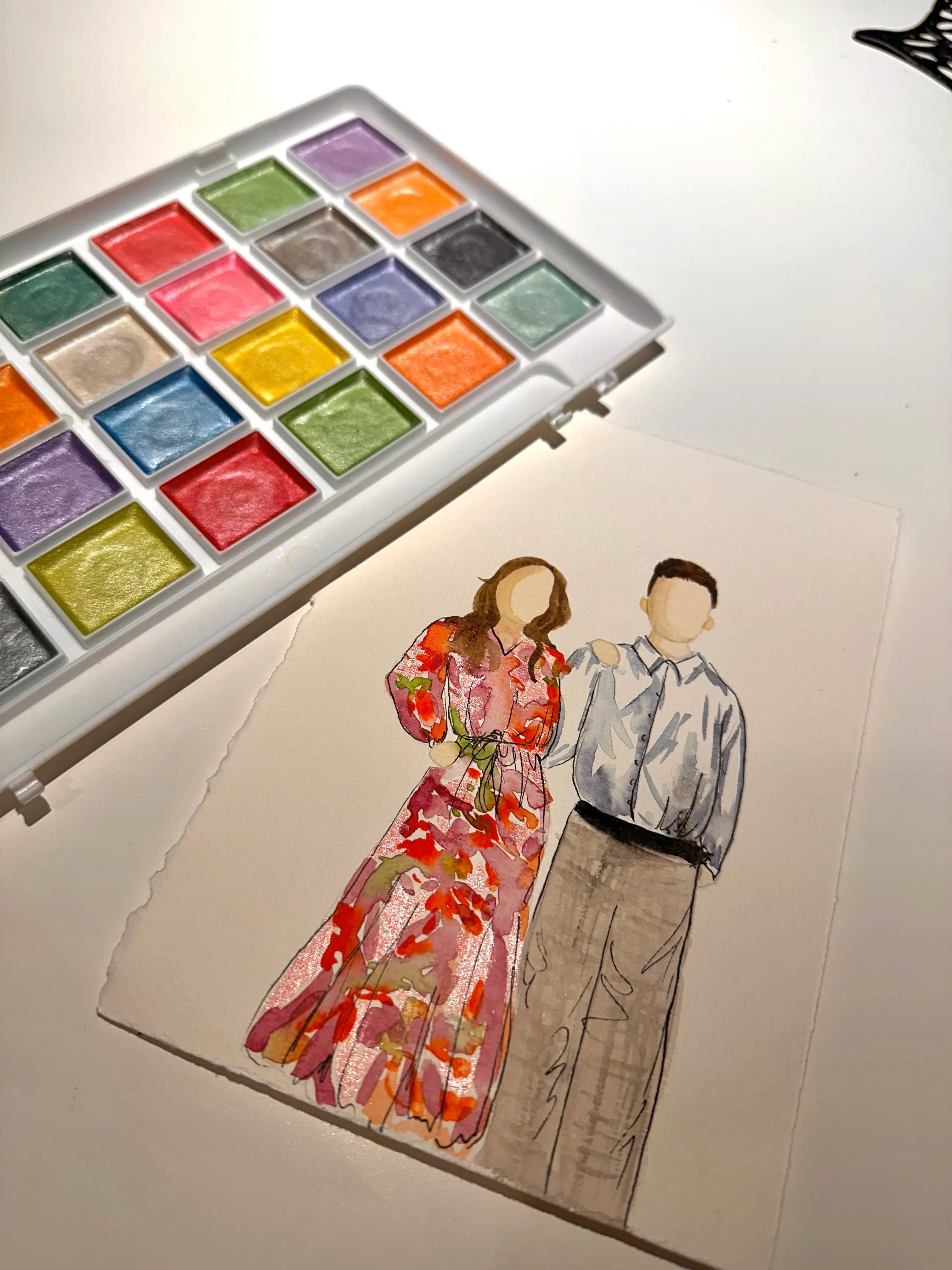 Aquarelle en direct d'un couple peinte par Gabrielle, posée à côté de sa palette de couleurs